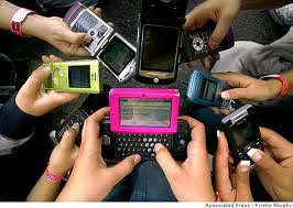 A picture of lots of cellphones and people using them